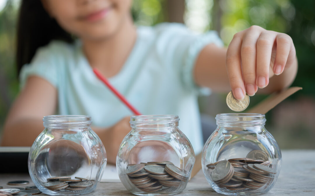 Cute asian little girl playing with coins making stacks of money,kid saving money into piggy bank, into glass jar. Child counting his saved coins, Children learning about for the future concept.